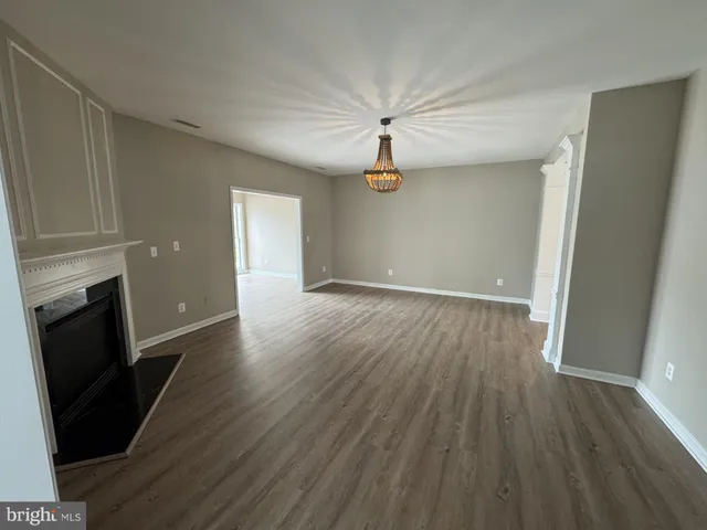 an empty room with wooden floor and fireplace