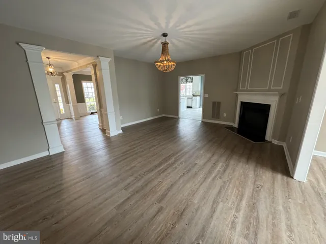 an empty room with wooden floor fireplace and windows
