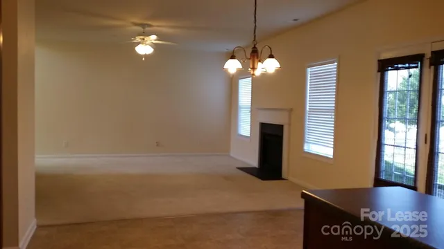 a view of a livingroom with a fireplace a chandelier and windows