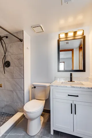 a bathroom with a granite countertop toilet sink and mirror