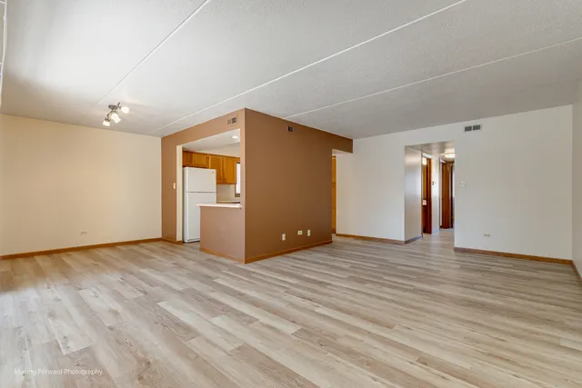 a view of an empty room with wooden floor and closet
