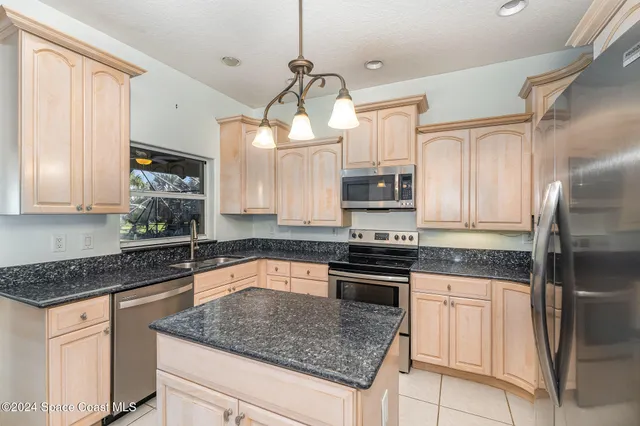 a kitchen with stainless steel appliances granite countertop a sink a stove a refrigerator cabinets and living room view