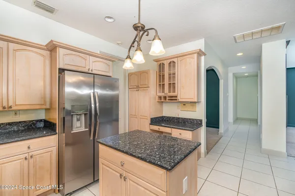 a kitchen with stainless steel appliances granite countertop a refrigerator a oven and white cabinets