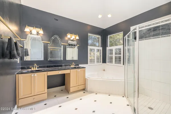 a bathroom with a tub a double vanity sink a mirror and a shower