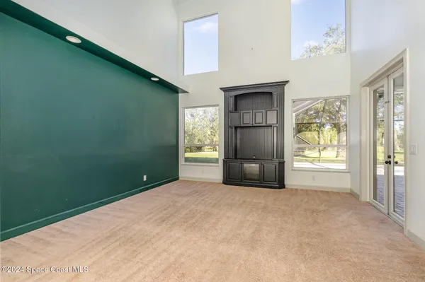 a view of an empty room with a window and refrigerator