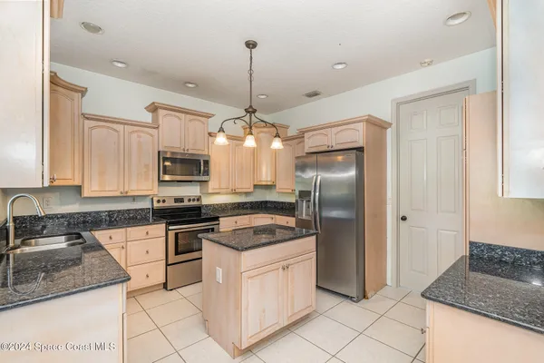 a kitchen with stainless steel appliances granite countertop a refrigerator a sink dishwasher a stove and white cabinets with wooden floor