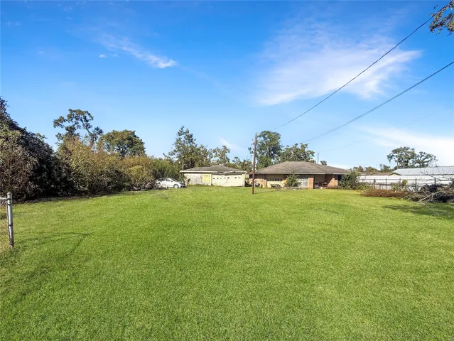a view of a white house with a big yard and potted plants