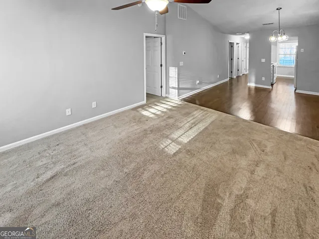 a view of a room with a chandelier fan and kitchen view