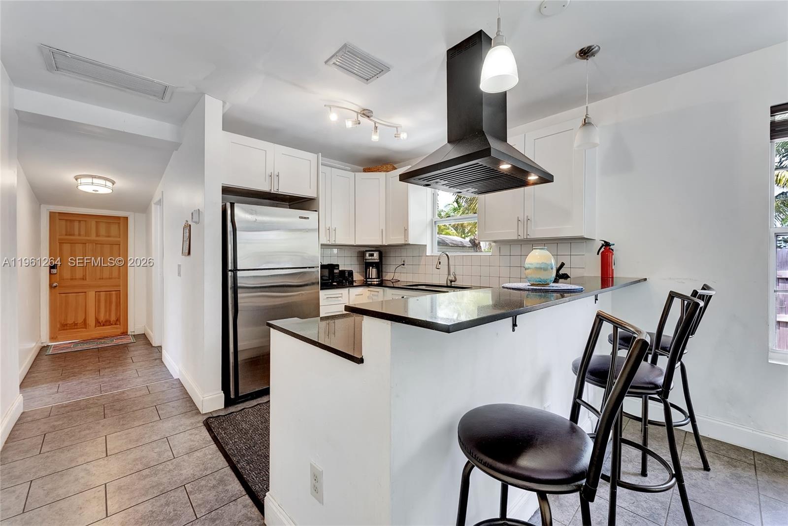 107 Stirling Road Dania Beach, FL 33004 - Photo 7 of 17 a kitchen with stainless steel appliances granite countertop a sink a stove a refrigerator and island with wooden floor