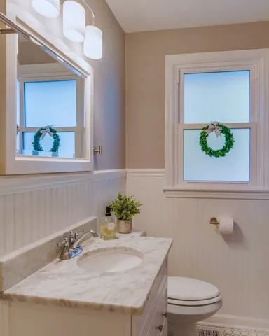 a bathroom with a granite countertop sink a toilet and a mirror
