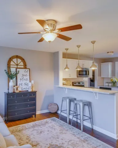a living room with stainless steel appliances furniture a chandelier and a view of kitchen