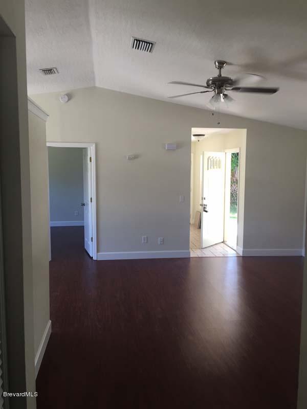 630 Weaver Road Southwest Palm Bay, FL 32908 - Photo 9 of 11 an empty room with wooden floor chandelier fan and windows