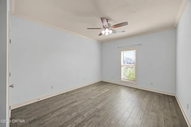 an empty room with wooden floor fan and windows