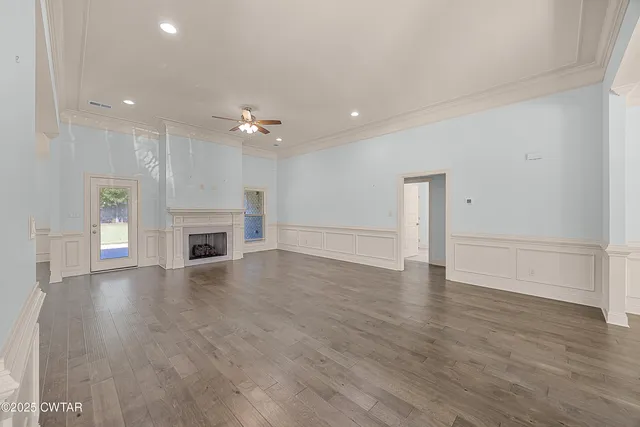 an empty room with wooden floor fireplace and windows