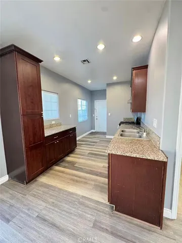 a view of kitchen with granite countertop sink and refrigerator