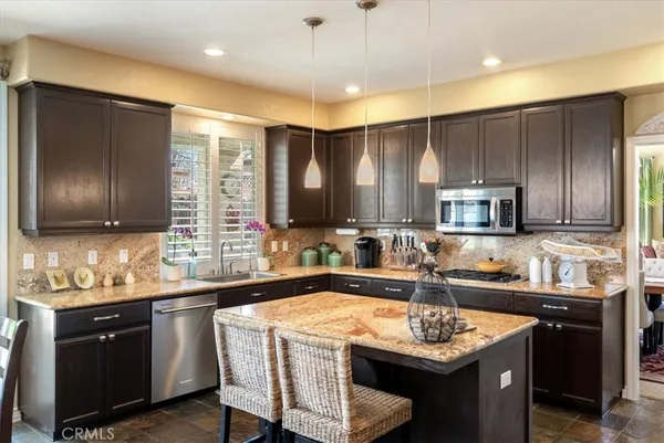 a kitchen with stainless steel appliances granite countertop a table chairs sink refrigerator and microwave