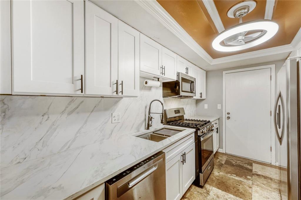 6851 Roswell Road, Unit M13 Atlanta, GA 30328 - Photo 12 of 28 a kitchen with stainless steel appliances granite countertop a sink a stove a microwave a refrigerator and cabinets