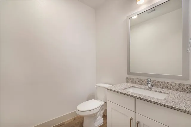 a bathroom with a granite countertop sink toilet and a mirror
