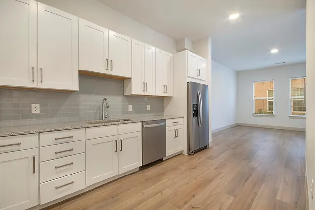 a kitchen with granite countertop white cabinets and refrigerator