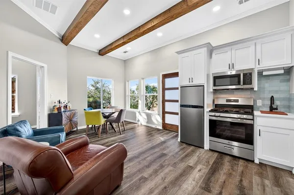 a living room with stainless steel appliances furniture and a wooden floor