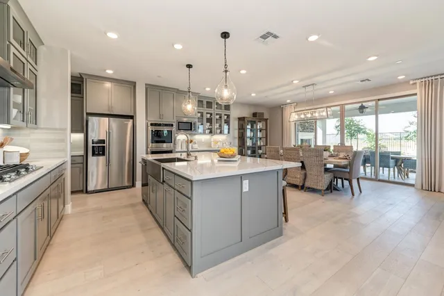 a kitchen with a dining table chairs stainless steel appliances and cabinets