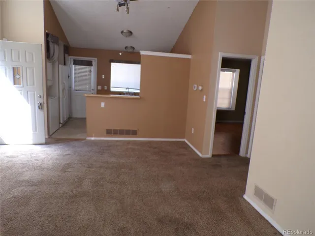 an empty room with staircase and a hallway