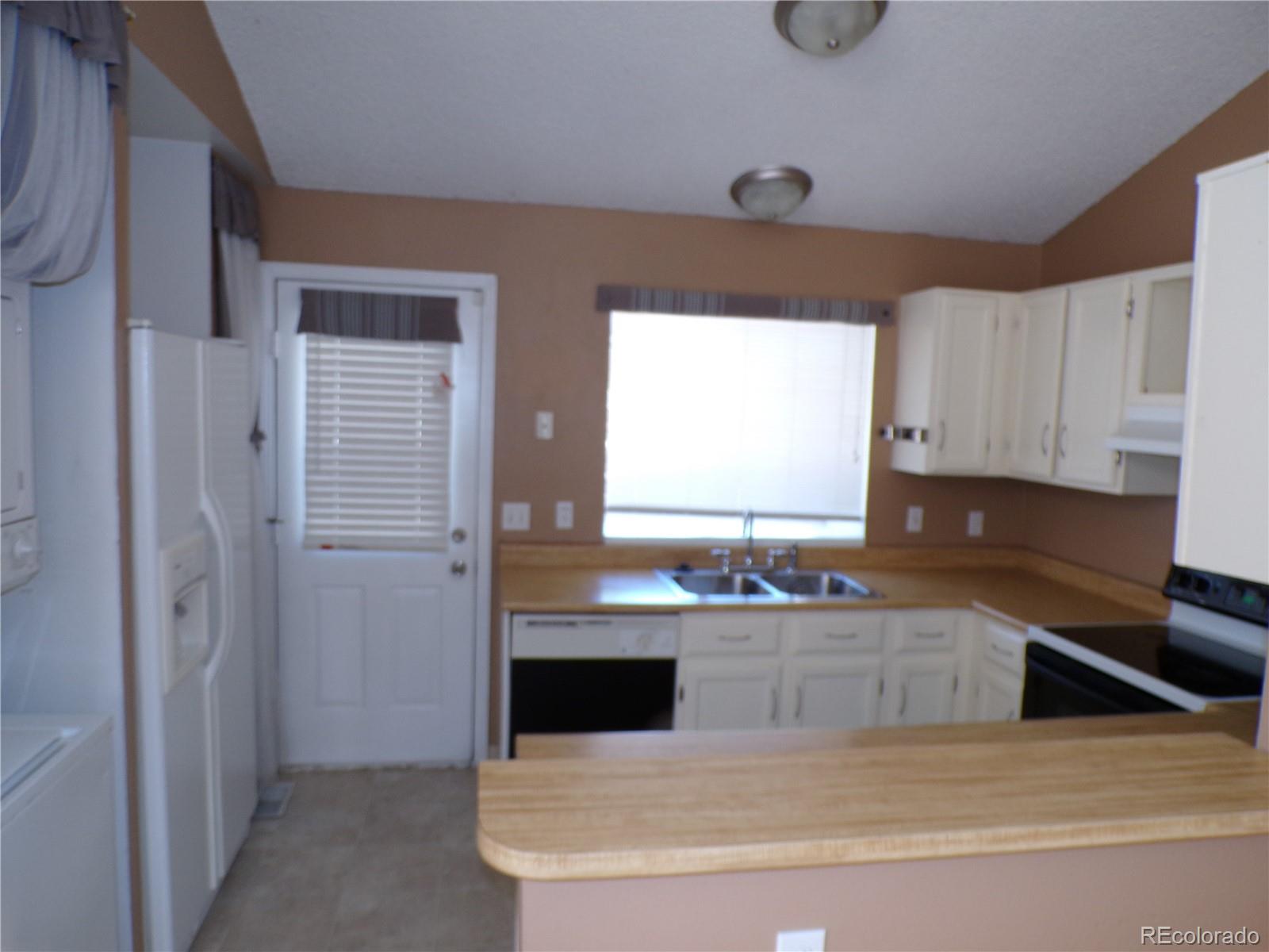 9644 West Chatfield Avenue, Unit A Littleton, CO 80128 - Photo 8 of 11 a kitchen with stainless steel appliances a sink a stove a refrigerator a window and cabinets