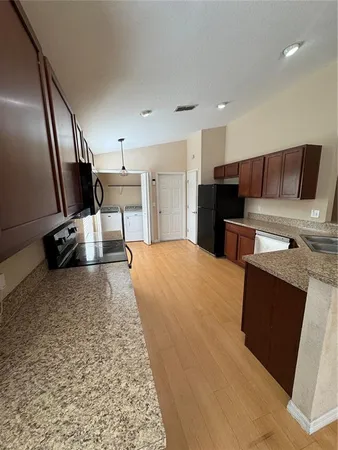 a living room with stainless steel appliances kitchen island granite countertop a refrigerator sink and cabinets