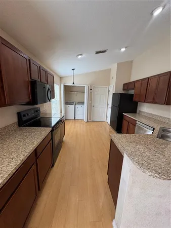 a large kitchen with kitchen island granite countertop wooden cabinets a granite counter top and a stove