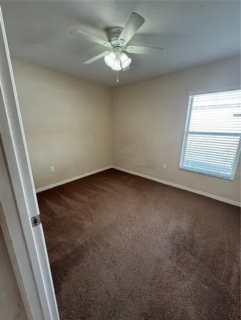 en empty room with windows and ceiling fan