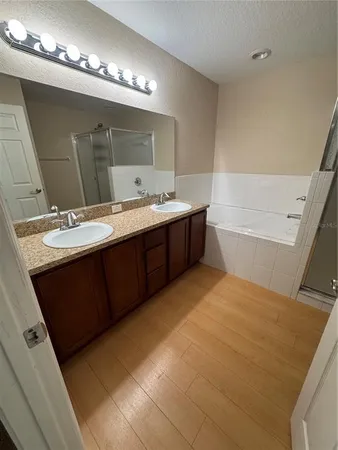 a spacious bathroom with a double vanity sink a mirror and a bathtub