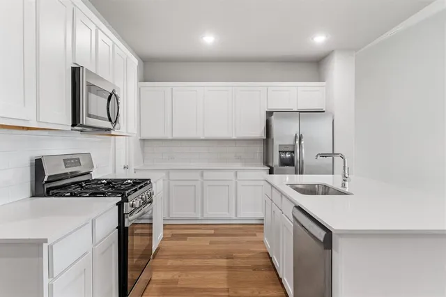 a kitchen with stainless steel appliances granite countertop a sink stove and cabinets
