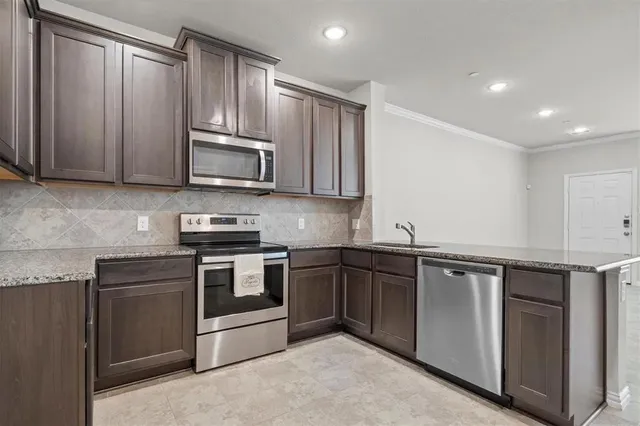 a kitchen with granite countertop wooden cabinets stainless steel appliances and a sink