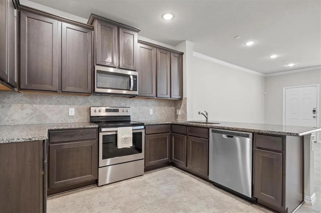 3300 Becker Drive Denton, TX 76207 - Photo 11 of 28 a kitchen with granite countertop wooden cabinets stainless steel appliances and a sink