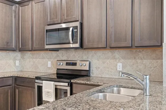 a kitchen with granite countertop a sink stove and cabinets