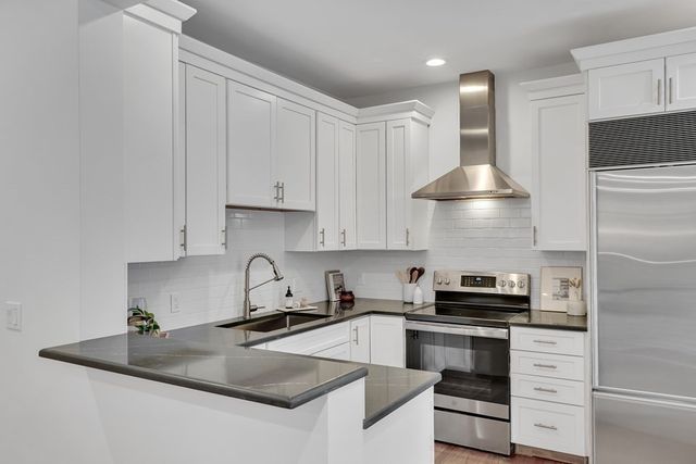 a kitchen with granite countertop white cabinets and stainless steel appliances