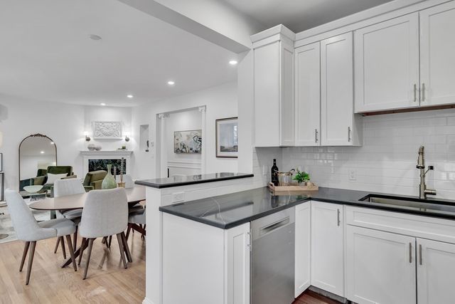 a kitchen with white cabinets and sink