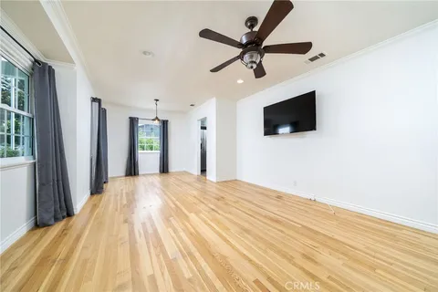a view of a room with wooden floor a ceiling fan and windows