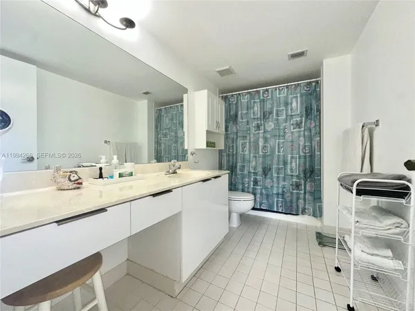a bathroom with a double vanity sink a toilet a mirror and shower
