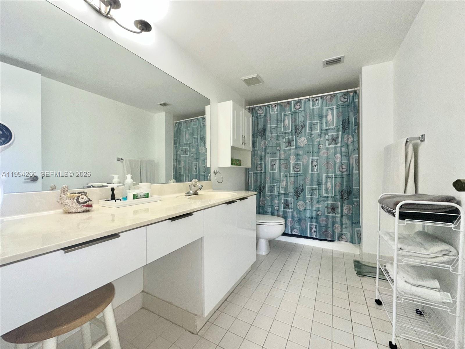 17801 North Bay Road, Unit 513 Sunny Isles Beach, FL 33160 - Photo 4 of 9 a bathroom with a double vanity sink a toilet a mirror and shower