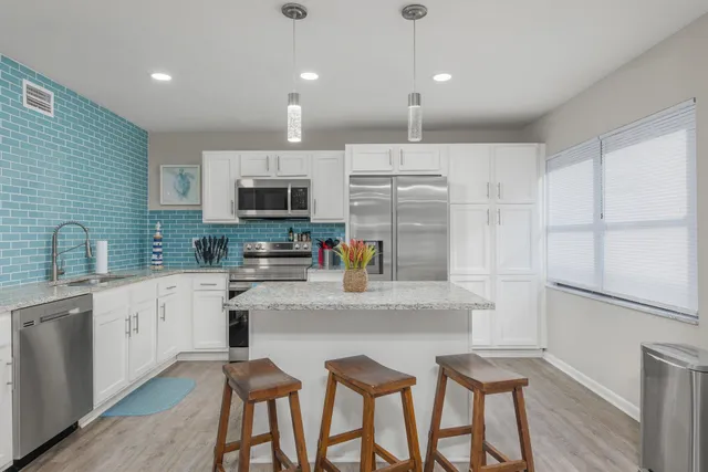 a kitchen with granite countertop white cabinets and stainless steel appliances