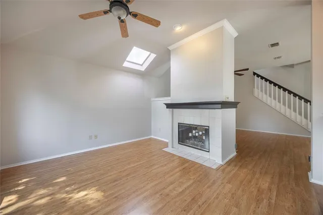 a view of an empty room with wooden floor and a fireplace