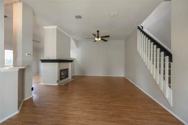 a view of an empty room with wooden floor and a fireplace