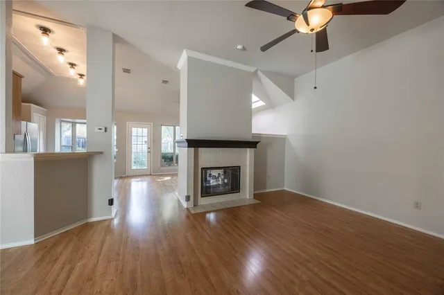 an empty room with wooden floor a fireplace and windows