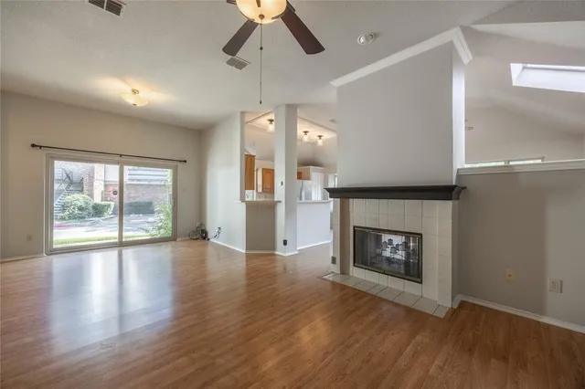 an empty room with wooden floor fireplace and windows
