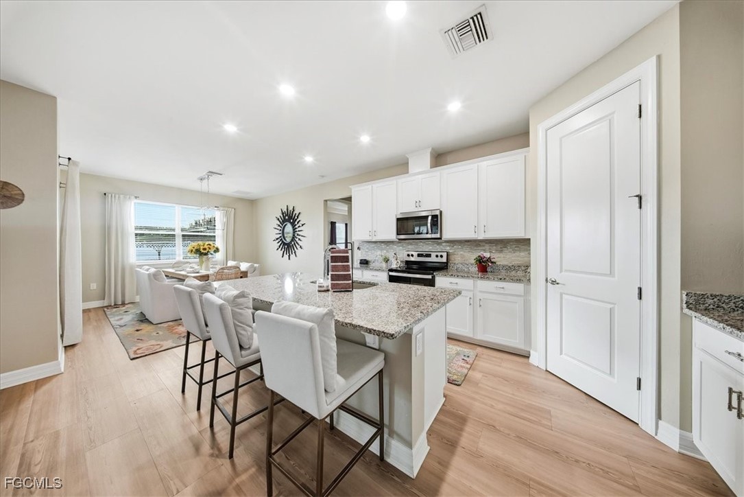 16128 Lotus Way Punta Gorda, FL 33982 - Photo 4 of 49 a kitchen with white cabinets and stainless steel appliances