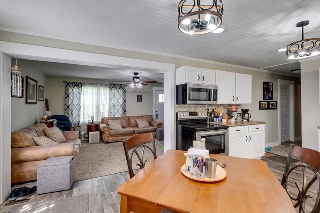 a kitchen with stainless steel appliances granite countertop a stove a kitchen island a dining table and chairs with wooden floor