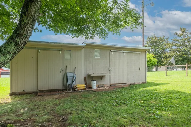 a view of a backyard with a barn and a large tree