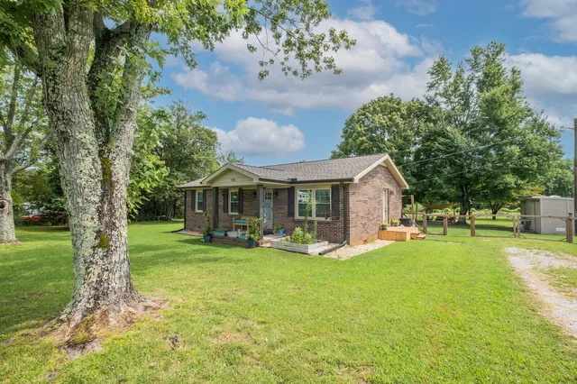 a view of a house with a big yard and large trees