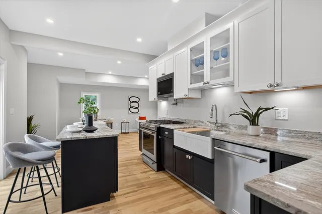 a kitchen with stainless steel appliances granite countertop a stove a sink dishwasher a microwave oven and a dining table with wooden cabinet